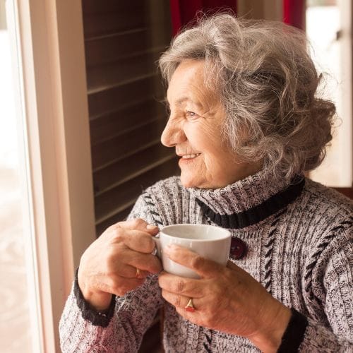 Femme âgée souriante buvant un café