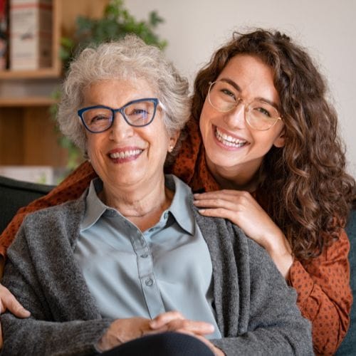 Deux femmes souriantes ensemble sur un canapé.