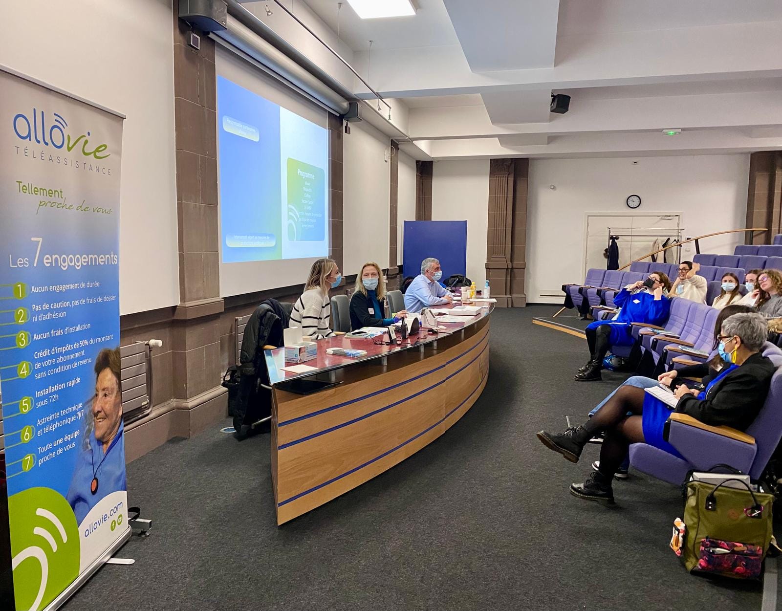 Conférence sur téléassistance avec présentation et participants masqués.