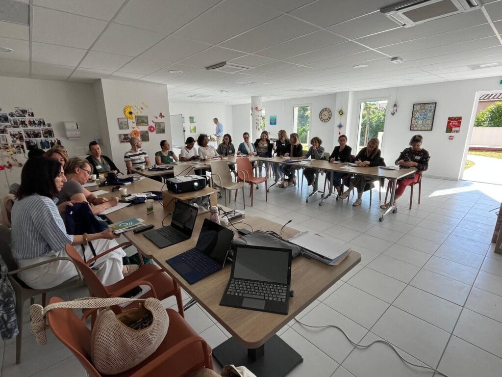 Groupe en réunion autour de grandes tables.
