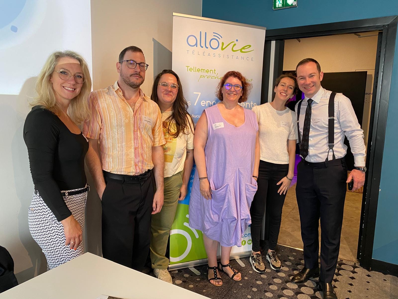 Groupe posant devant une affiche Allovie Téléassistance.