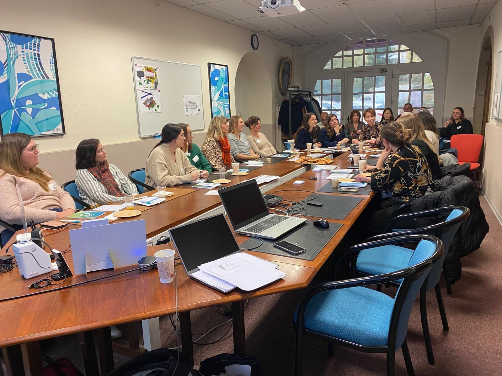 Réunion d'équipe autour d'une grande table en salle.