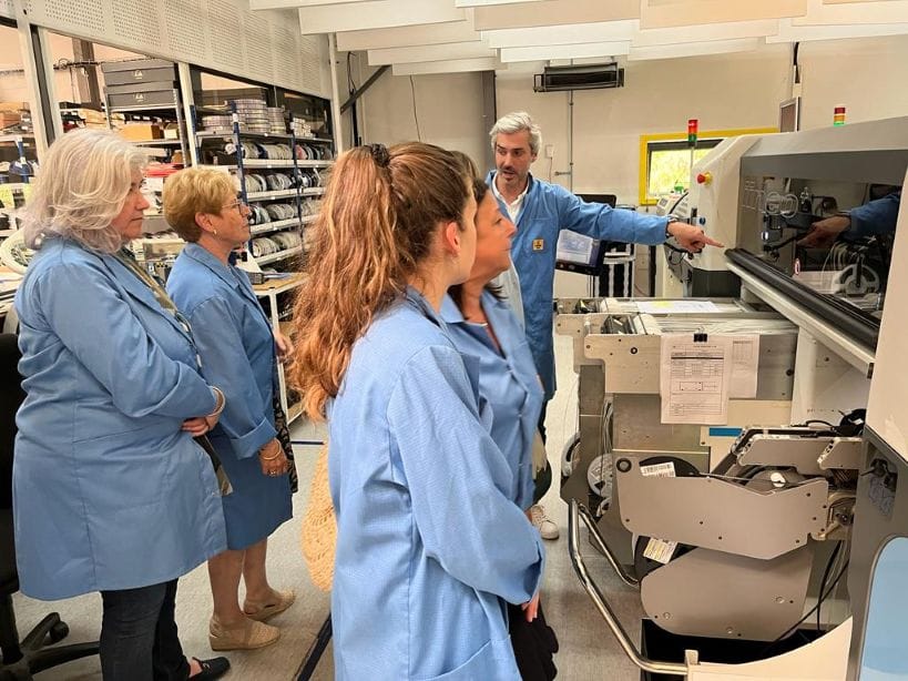 Personnes en uniforme bleu autour d'une machine industrielle.