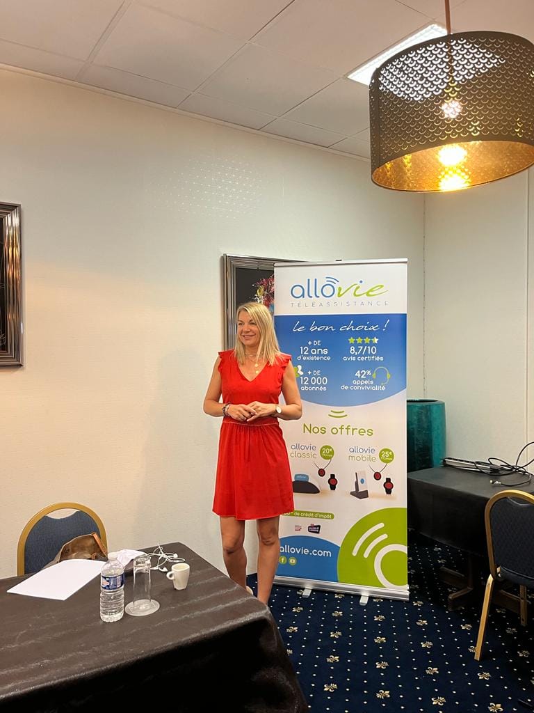 Femme en présentation devant un stand Allovie.