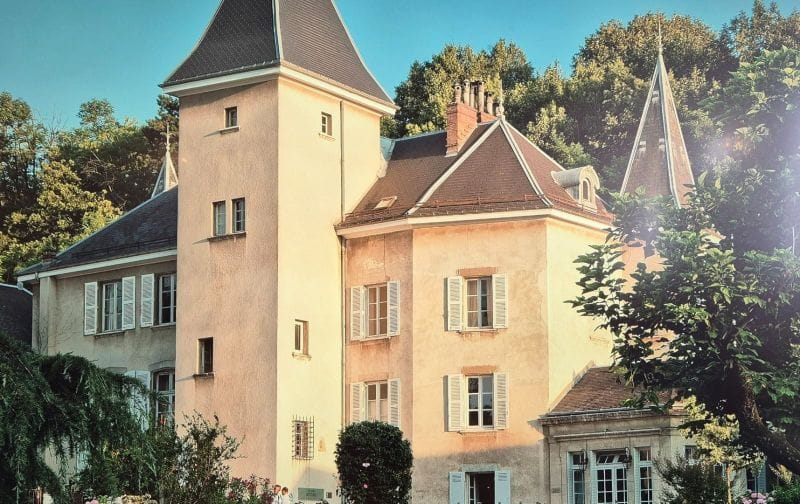 Château français ensoleillé entouré de verdure.