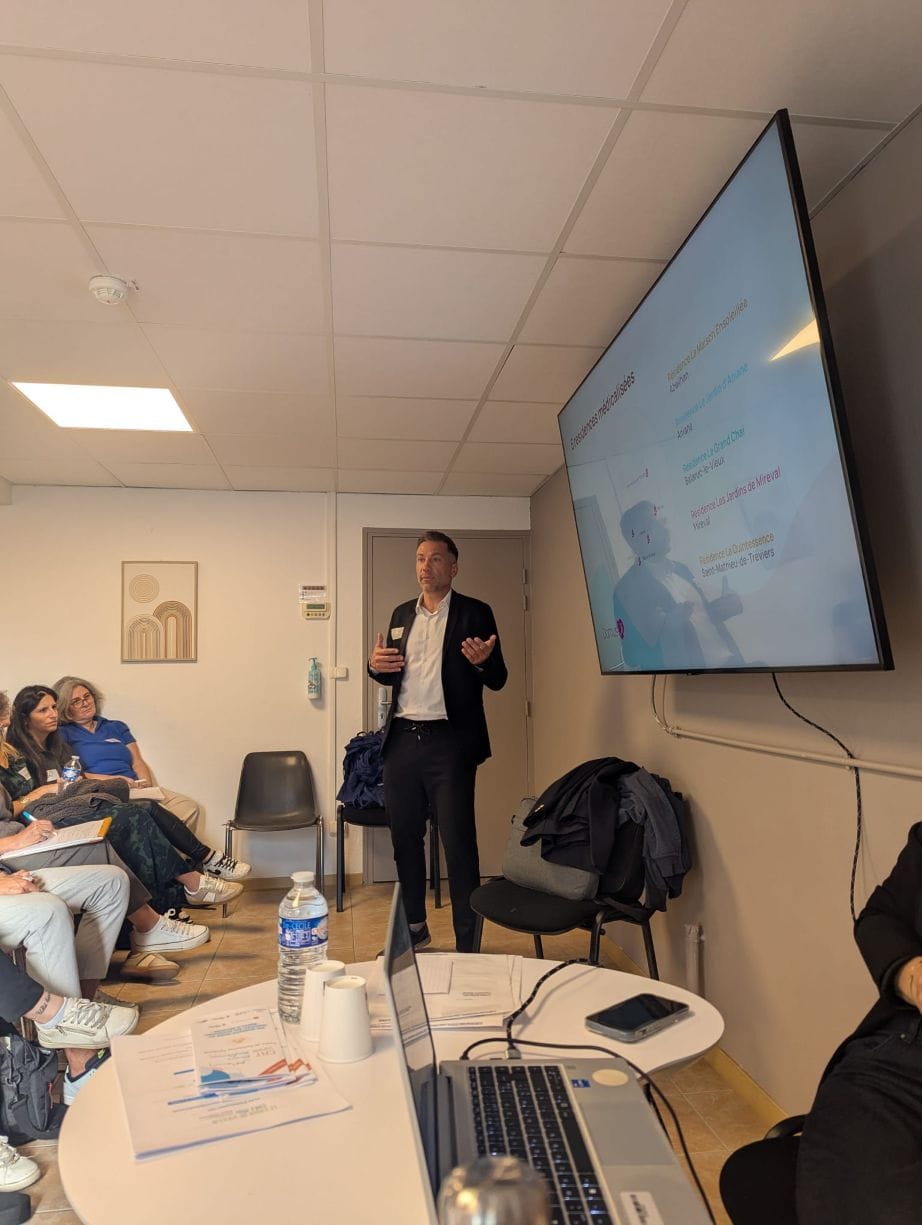 Homme présentant devant un public avec diapositive.