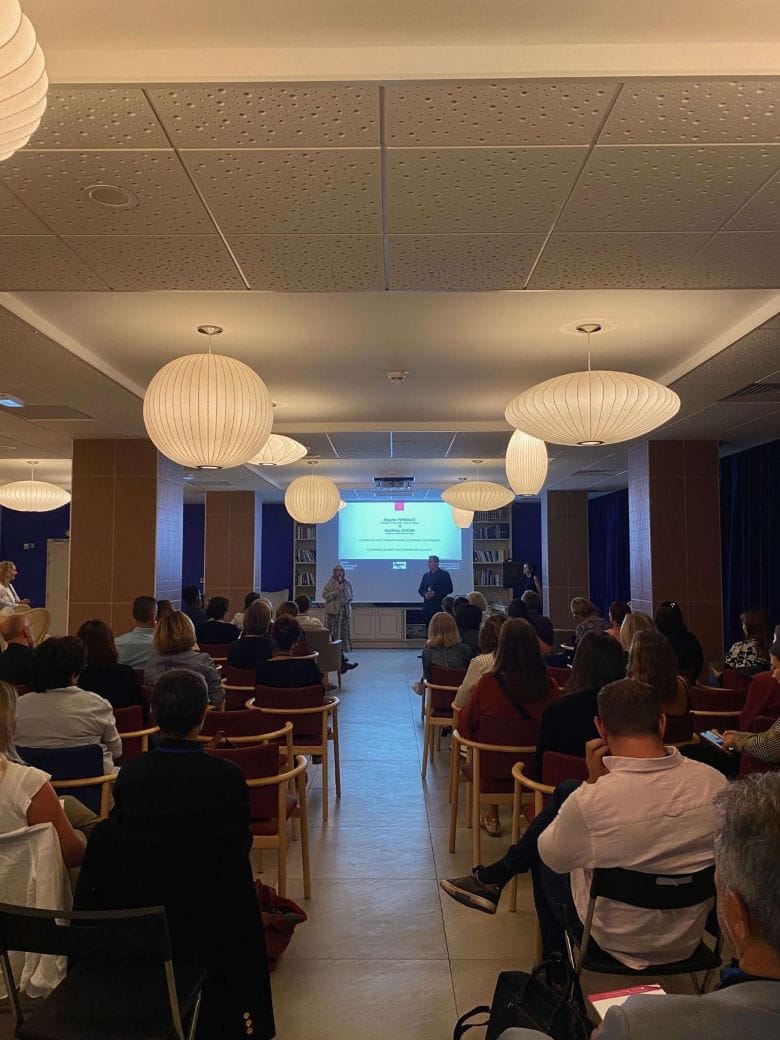 Conférence en salle avec nombreux participants assis.