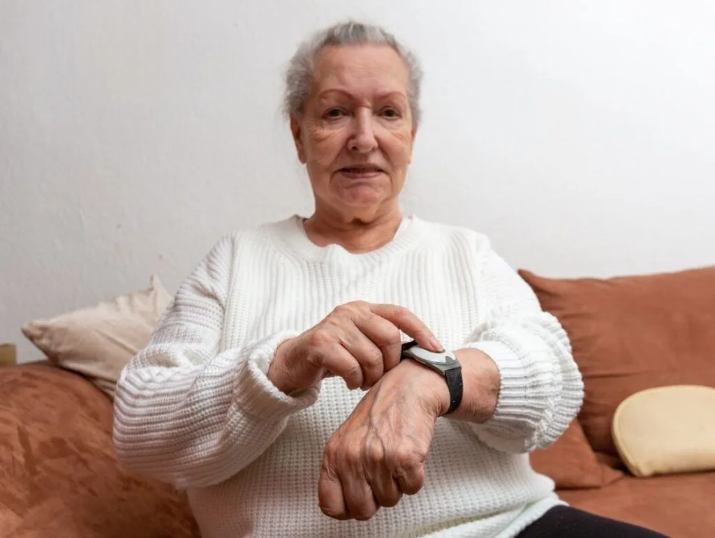 Femme vérifiant sa montre connectée sur canapé.