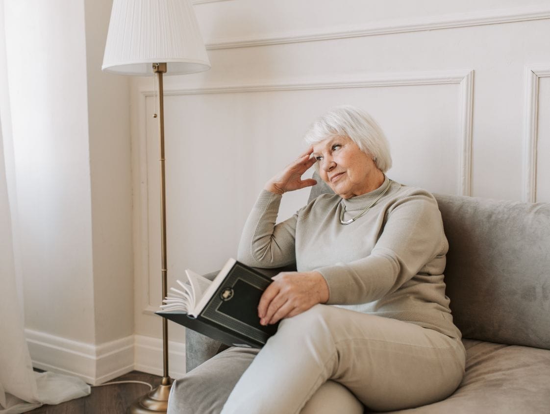 femme senior avec livre sur sofa