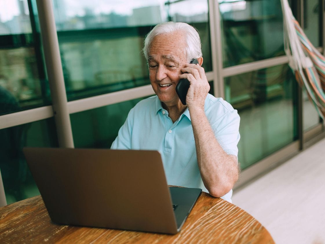 Homme souriant avec ordinateur et téléphone portable.