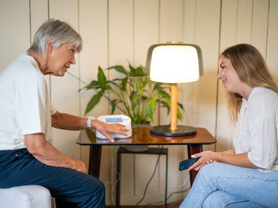 Deux femmes discutant autour d'une lampe sur table.