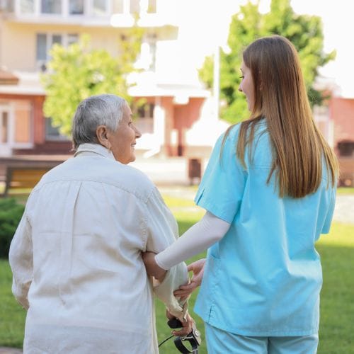 Aide-soignante aidant une personne âgée à marcher.