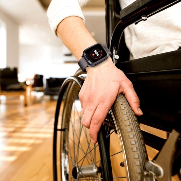 Main sur une roue de fauteuil roulant et montre.
