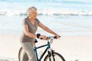 Femme souriante faisant du vélo sur la plage.