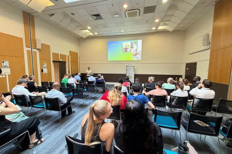 Conférence avec participants attentifs dans une salle.