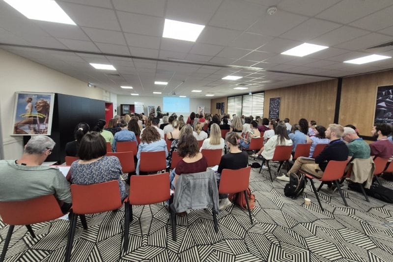Conférence avec public attentif dans une salle.