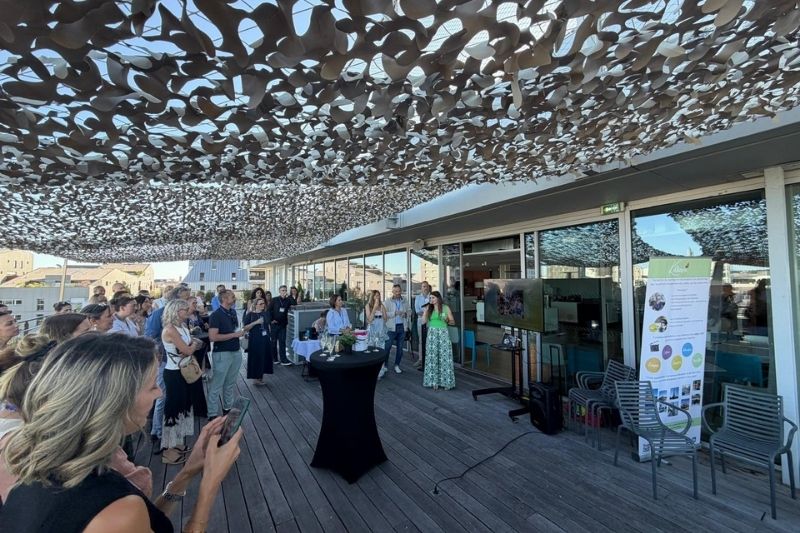 Réunion professionnelle sur une terrasse ensoleillée.