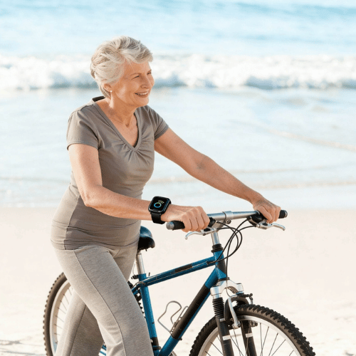 Femme souriante à vélo sur la plage.