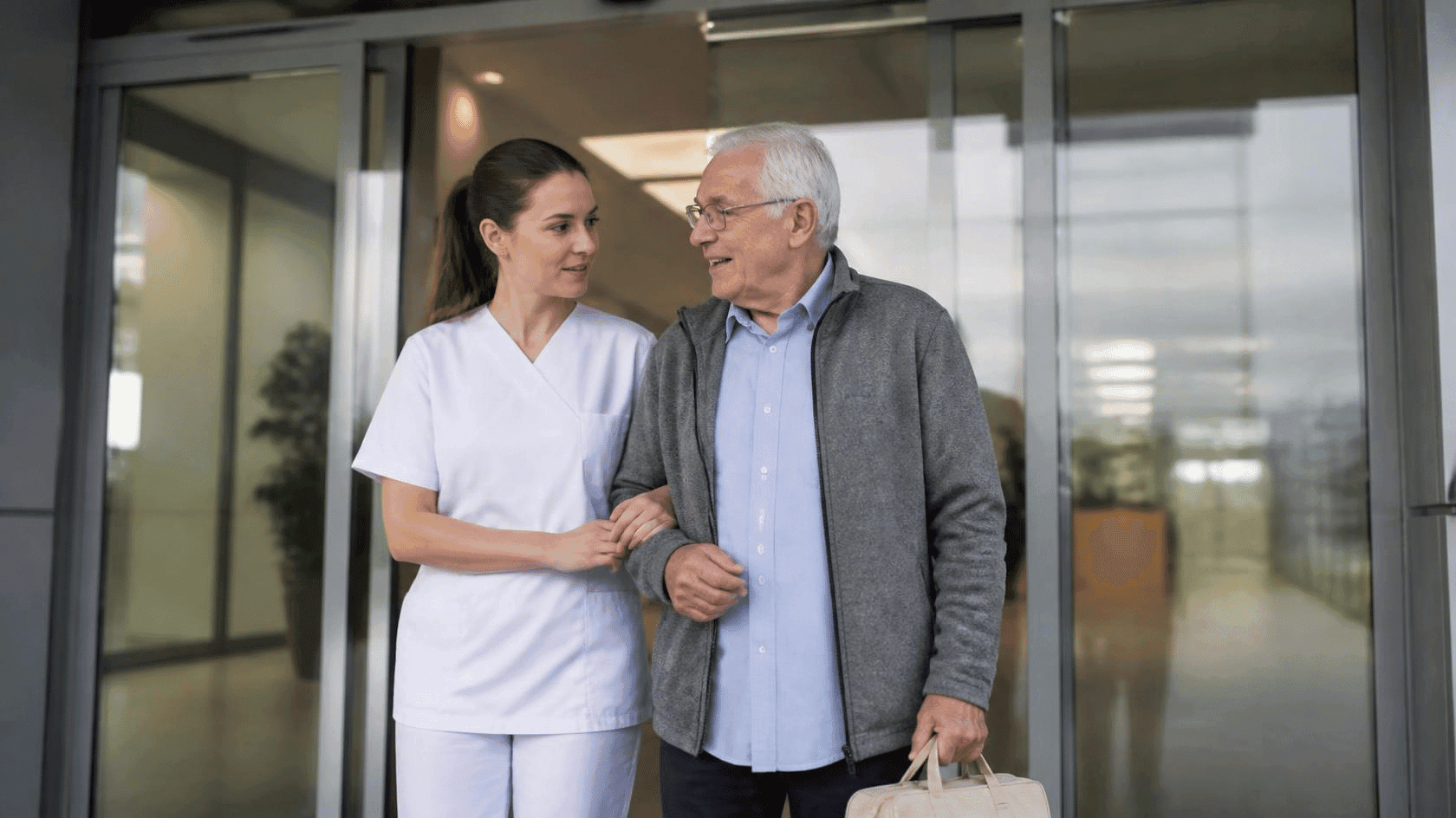 Infirmière accompagne homme âgé à l'extérieur d'un bâtiment.